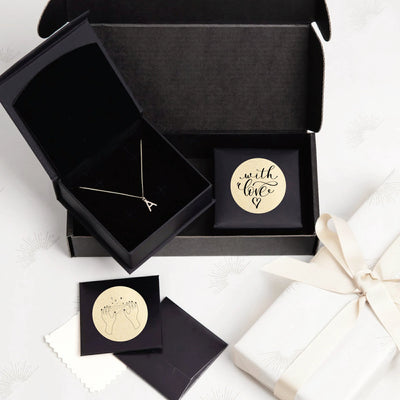Personalized letter necklace in black gift box with gold label stickers and wrapped present