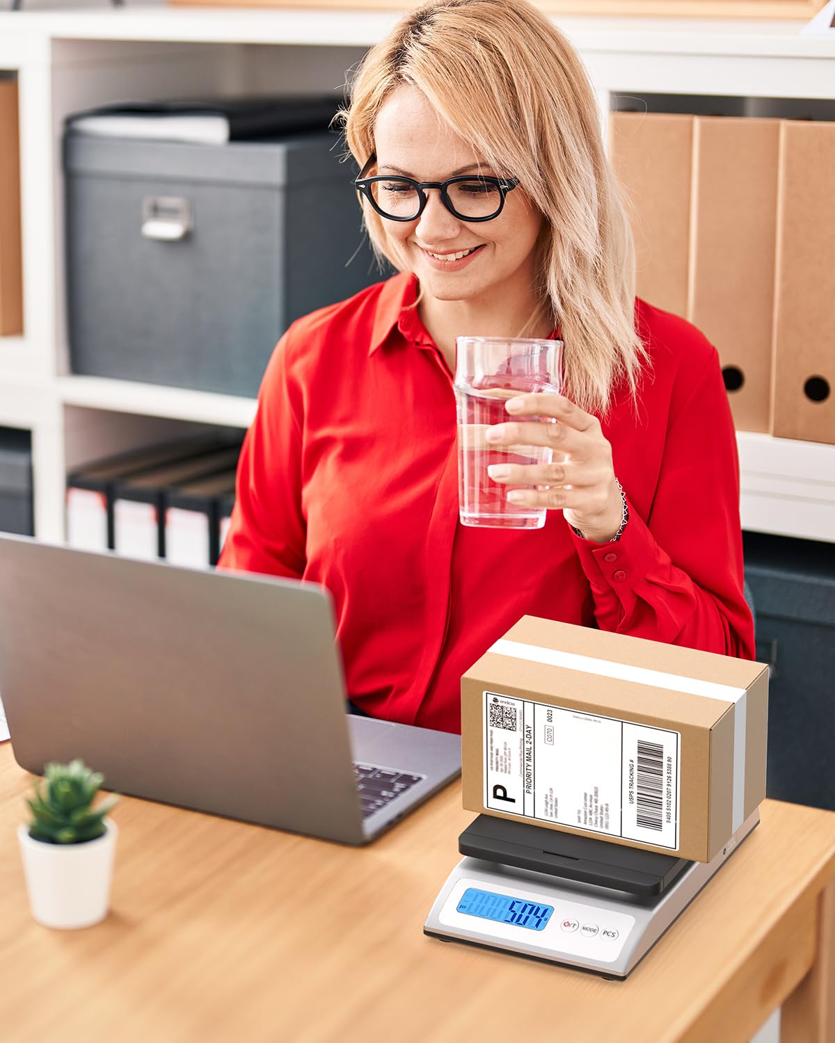 Woman using laptop with shipping box on digital postal scale, home office setting