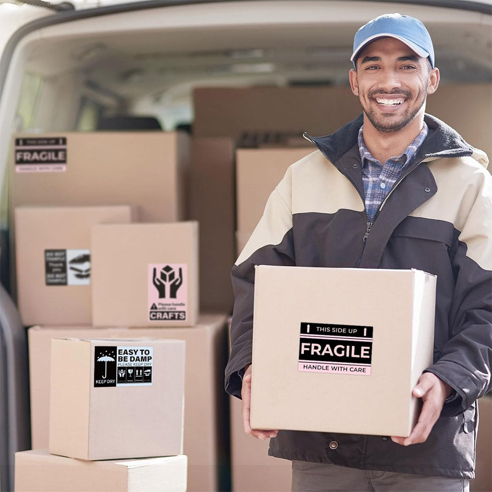 Delivery worker holding box with fragile shipping labels in front of van with packages.
