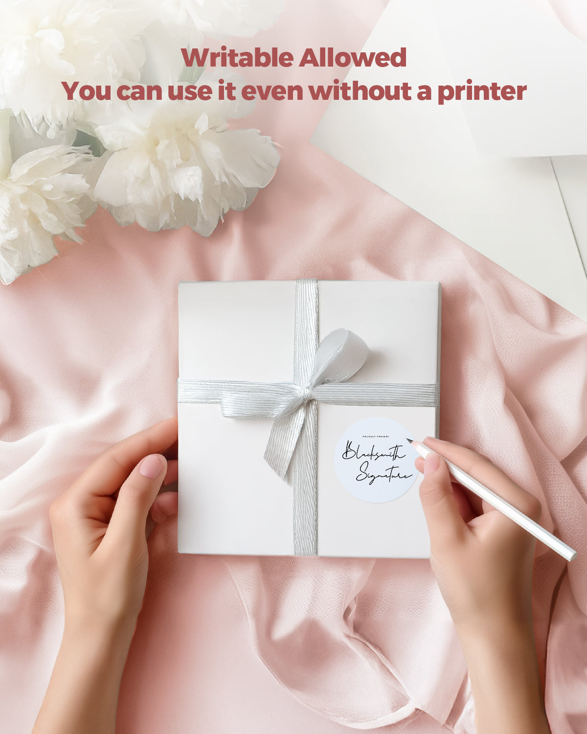 Hand writing on writable round label sticker on gift box with ribbon on pink fabric background